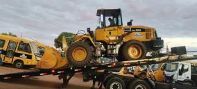 Guincho plataforma em Abadia de Goiás transportando uma retroescavadeira amarela.