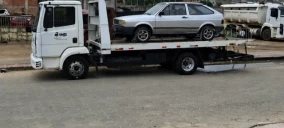 Guincho plataforma estacionado na rua em São Mateus, transportando um carro prata.