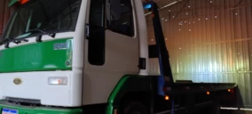 Guincho de plataforma verde e branco estacionado em um galpão em São Bento do Sul.