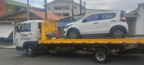 Guincho plataforma em Taubaté transportando um carro branco, estacionado na rua.