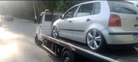 Guincho plataforma transportando um carro prata, estacionado em uma rua em Franco da Rocha.