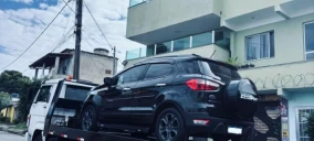 Guincho plataforma em Belo Horizonte transportando um carro preto, estacionado na rua.