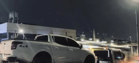 Guincho de plataforma transportando uma caminhonete branca em Belo Horizonte à noite.