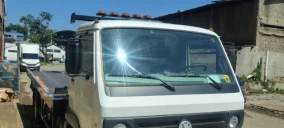 Guincho plataforma estacionado em área externa, com caminhão Volkswagen visível na parte frontal.