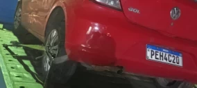 Guincho de plataforma transportando um veículo Volkswagen Gol vermelho em Caruaru, com parte traseira visível.