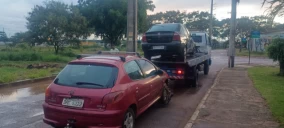 Guincho plataforma em Novo Gama transportando um carro preto sobre um caminhão, estacionado na rua.