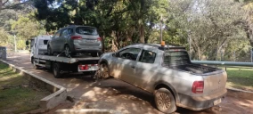 Guincho plataforma em Ibiúna transportando um carro cinza, enquanto um veículo pickup está parcialmente carregado.
