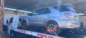 Veículo SUV prateado estacionado em guincho plataforma, localizado em Crato, com rodas erguidas.