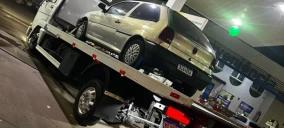Guincho plataforma com veículo prata estacionado, em posto de combustíveis em Bauru.