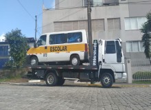 Guincho plataforma em Caxias do Sul transportando uma van escolar com pintura amarela e branca.