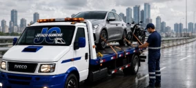 Guincho plataforma em Suzano, transportando um carro cinza e uma moto, com operador ajustando a carga.
