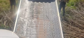 Guincho de plataforma em Carmo/RJ, com rampa visível e dois homens ao lado, sem veículo transportado aparente.