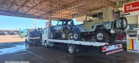 Guincho plataforma transportando dois veículos off-road em posto de combustíveis em Piraju, um deles com capota.