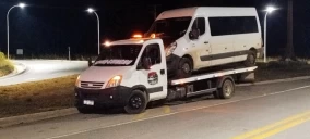 Guincho plataforma transportando uma van branca em Utinga, à noite, com luzes de emergência acionadas.