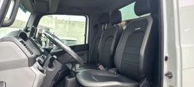 Interior de um caminhão guincho com assentos em couro preto e painel visível, sem veículo transportado aparente.