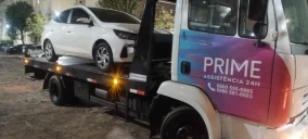 Guincho plataforma transportando um carro branco em São Ludgero.