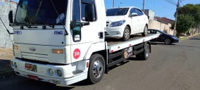 Guincho plataforma branco estacionado em Bauru, transportando um carro de cor prata.
