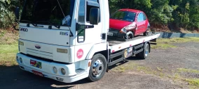 Guincho plataforma branco com um carro vermelho em cima, estacionado em área externa em Bauru.