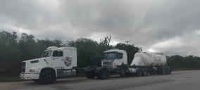 Guincho tipo plataforma estacionado na estrada, transportando um caminhão tanque em Capim Grosso, BA.
