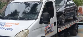 Guincho plataforma transportando um veículo preto, estacionado em Itaquaquecetuba.