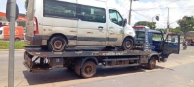 Guincho plataforma em Goiânia transportando uma van branca sobre sua carroceria, estacionado na rua.